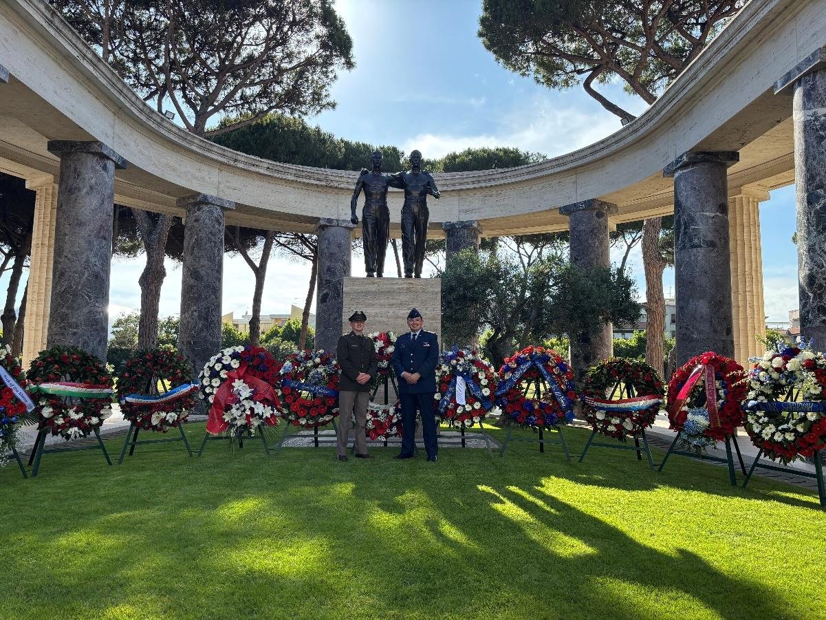 Two cadets beneath the colonnade at Sicily-Rome American Cemetery, surrounded by wreaths
