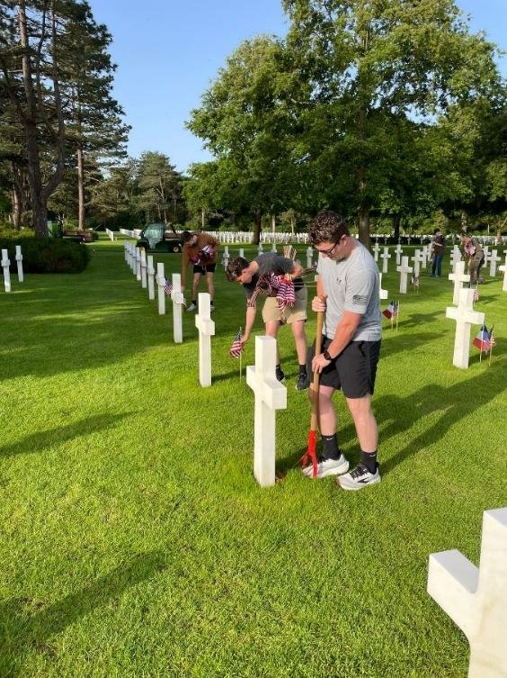 Fellows cleaning white marble headstones at an American military cemetery